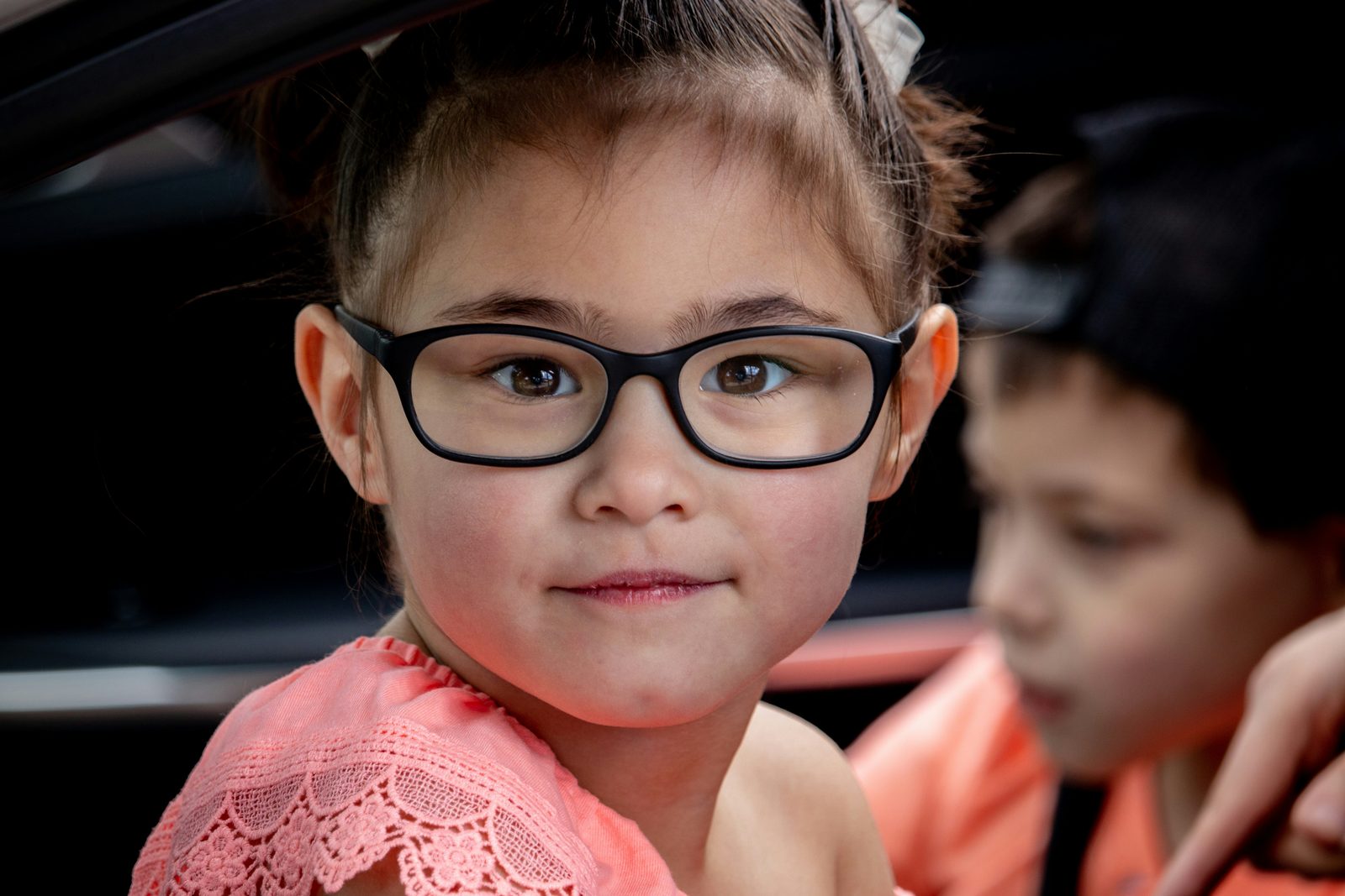 A young child in black-framed glasses smiling.