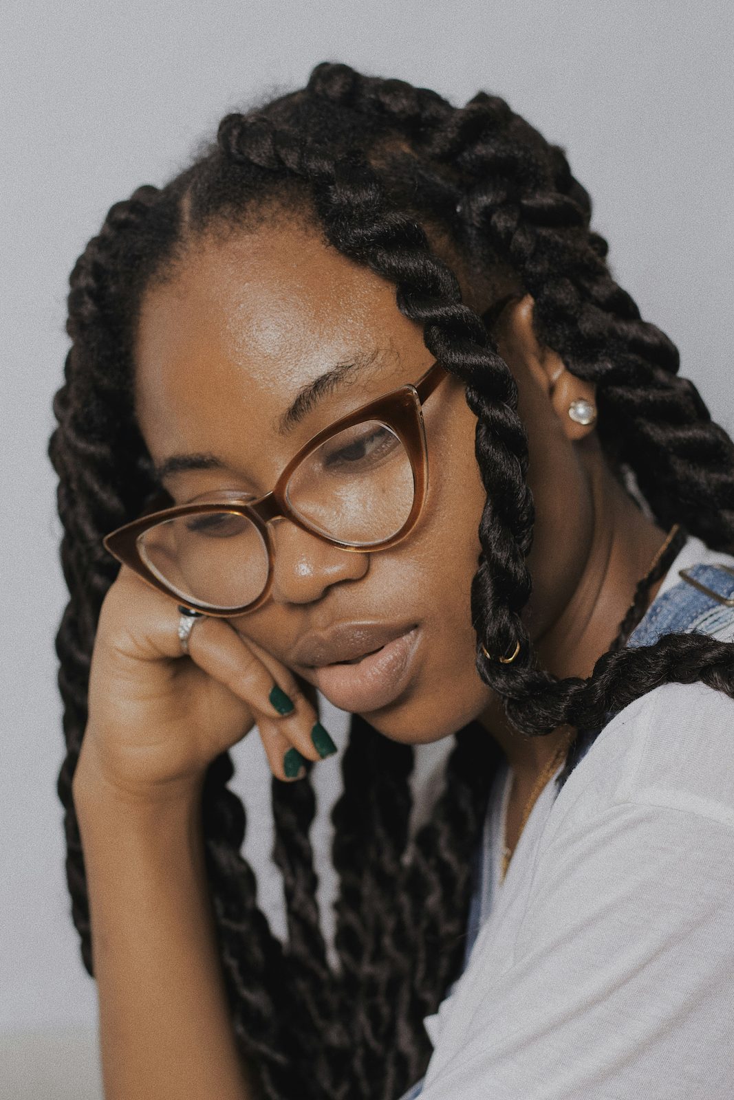 A woman in tortoiseshell glasses resting her chin on her hand, thinking.