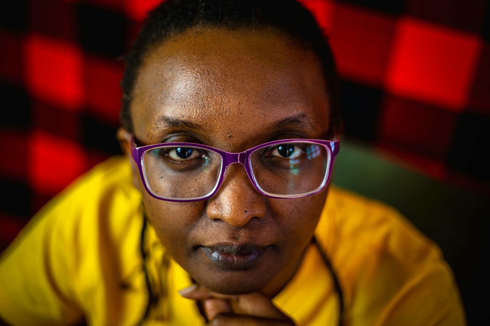 A woman in violet-framed glasses looking at the camera.