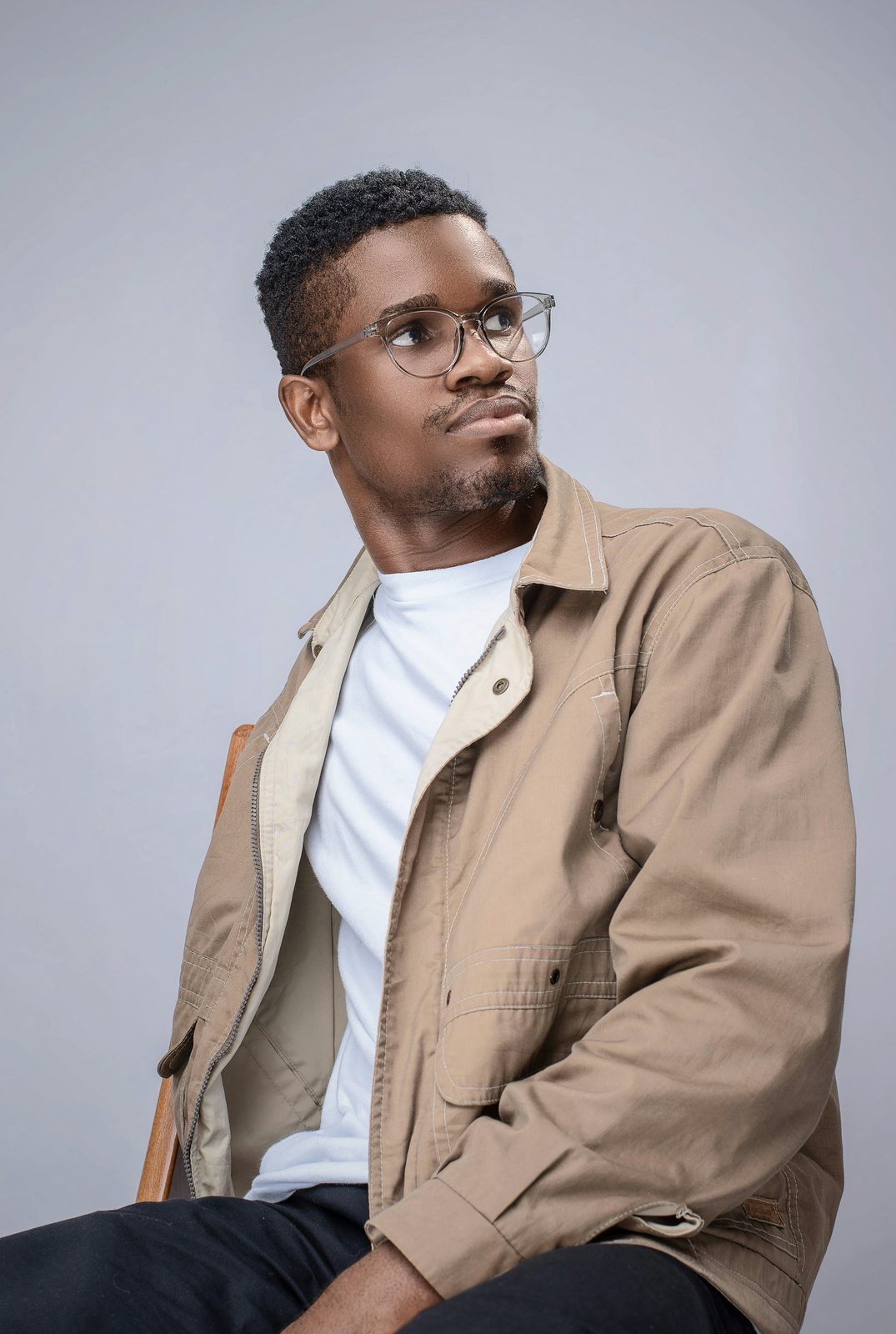 A man in round glasses looking upward, thinking.